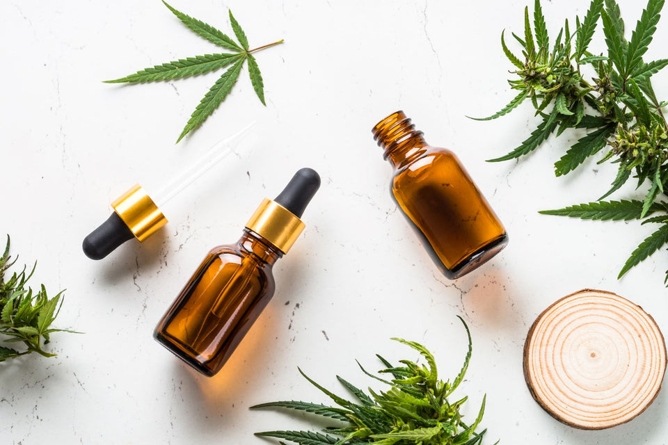 CBD oil bottles on a table with scattered cannabis leaves